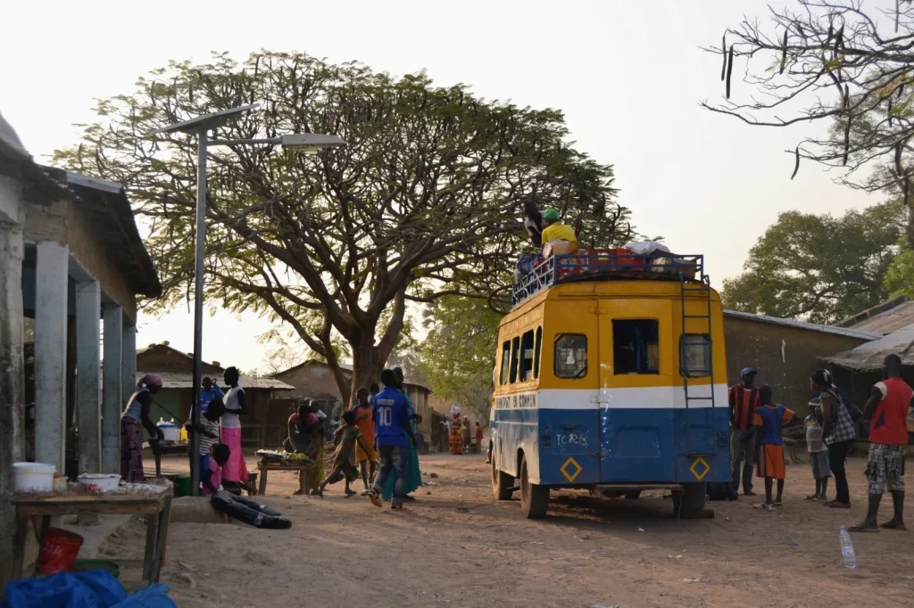 Autobús local rodeado de personas y puestos de venta en Senegal