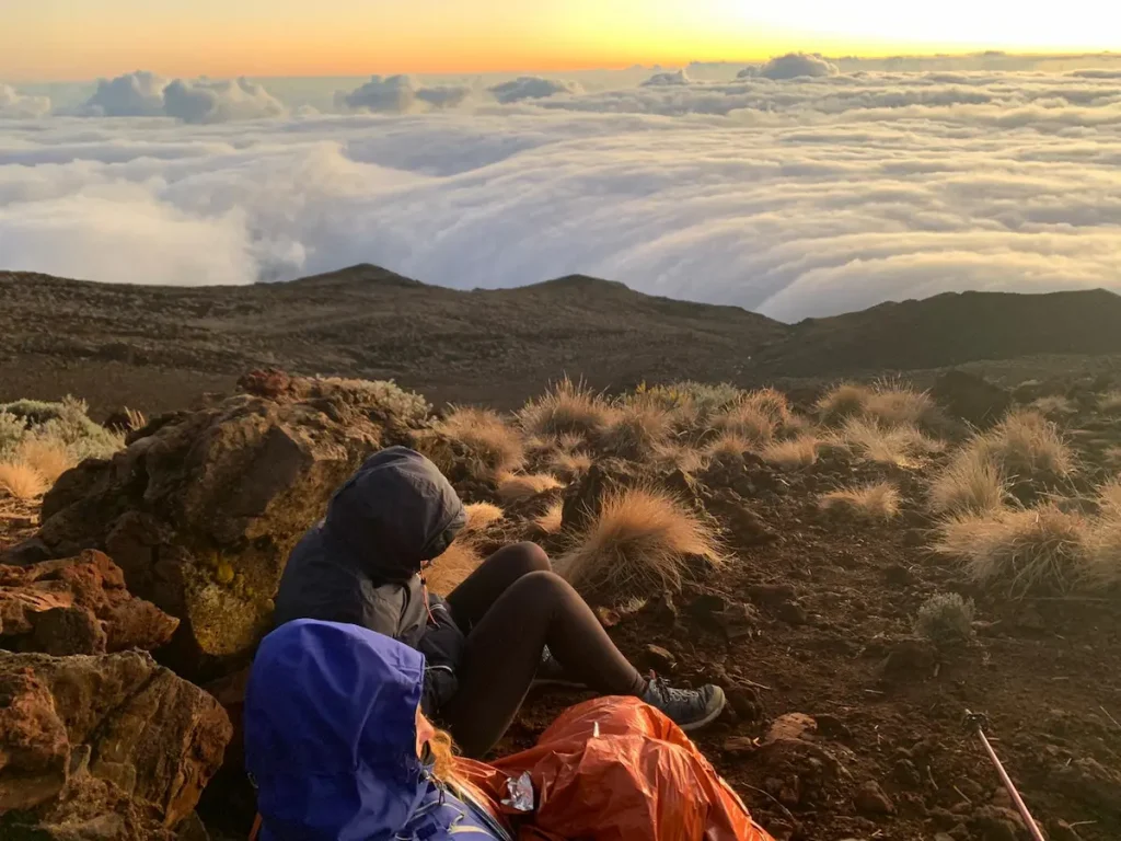 Paisaje de Cilaos, La Reunión Dos personas descansando en un paisaje de montaña sobre un mar de nubes en Cilaos, La Reunión