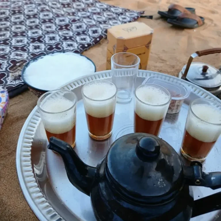 Bandeja con tetera y vasos de té servidos sobre la arena durante una parada en el desierto del Sáhara Occidental.